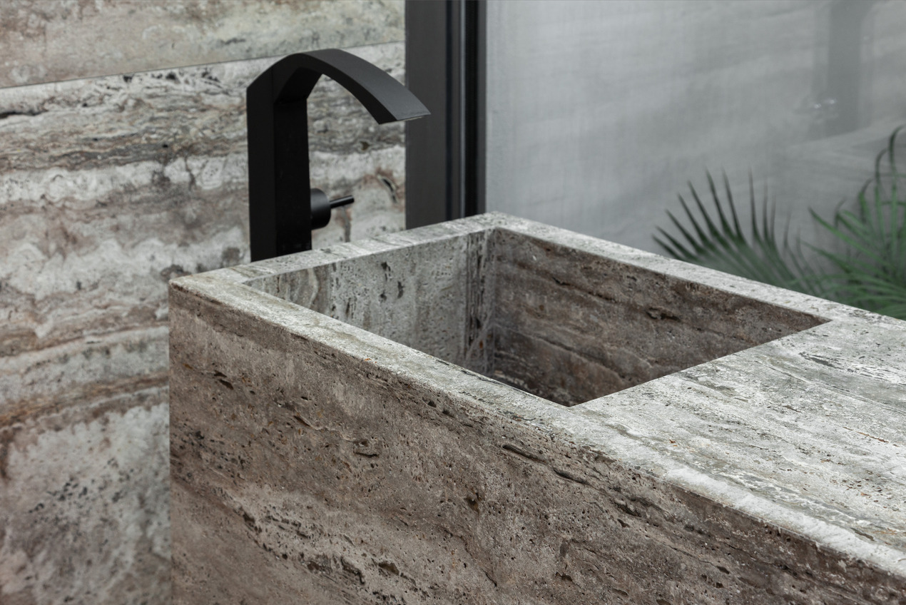 A square custom sink crafted with Travertino Silver, seamlessly blends with the surrounding walls.