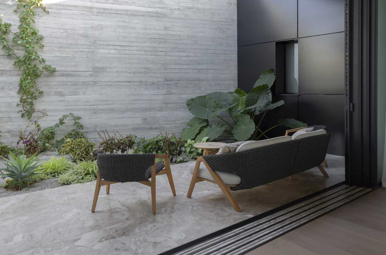 Modern outdoor patio with Karnis marble, vertical garden, and woven seating.