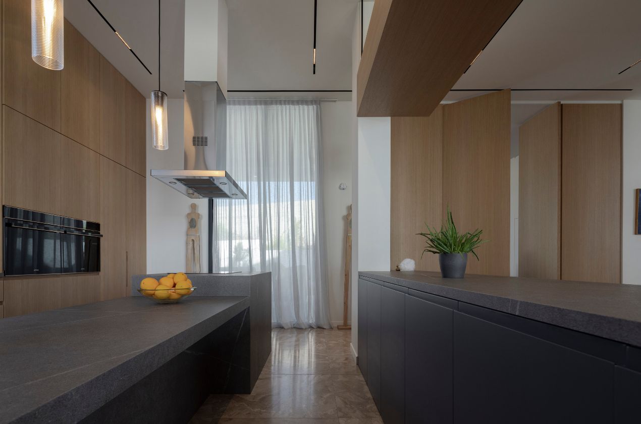 Senda MDi Kitchen Worktop Contemporary kitchen featuring a dark gray Senda MDi kitchen Worktop with clean lines, wood cabinetry, pendant lighting, and natural light filtering through sheer curtains.